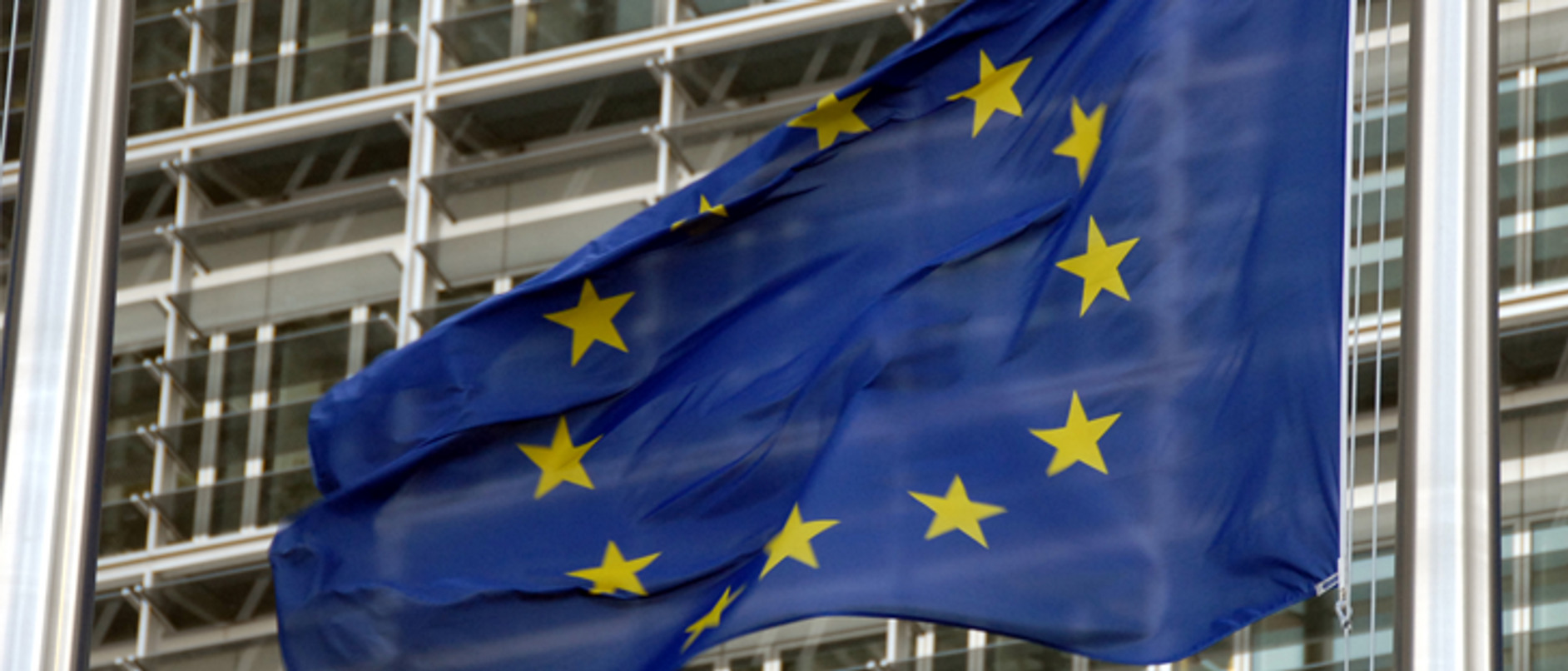 En europeisk flagga vajar framför en byggnad.