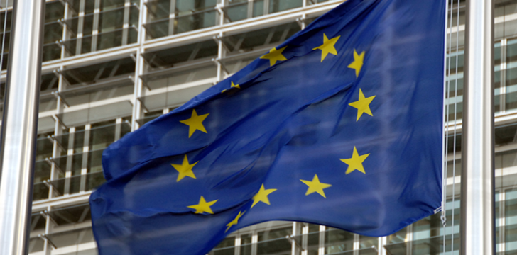 En europeisk flagga vajar framför en byggnad.