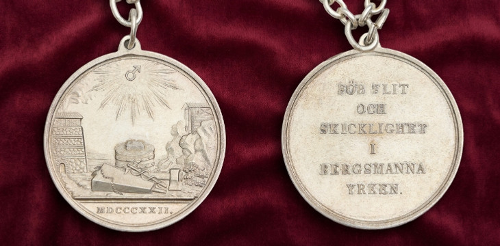 Två silvermedaljonger på en röd duk.