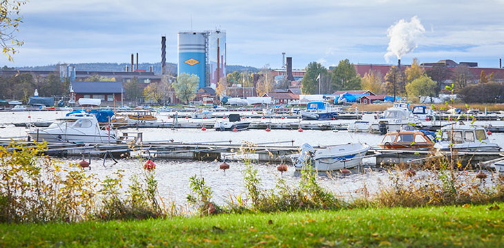 En hamn full av båtar intill en industri.
