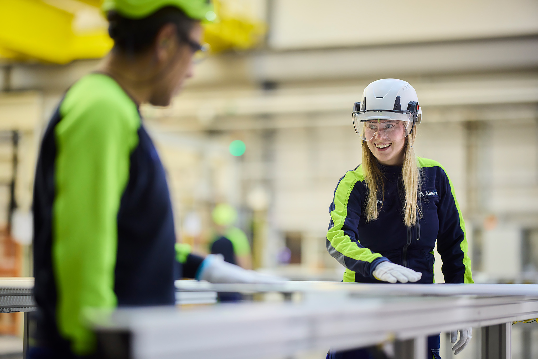 A woman in safety gear standing next to a man in a factory.