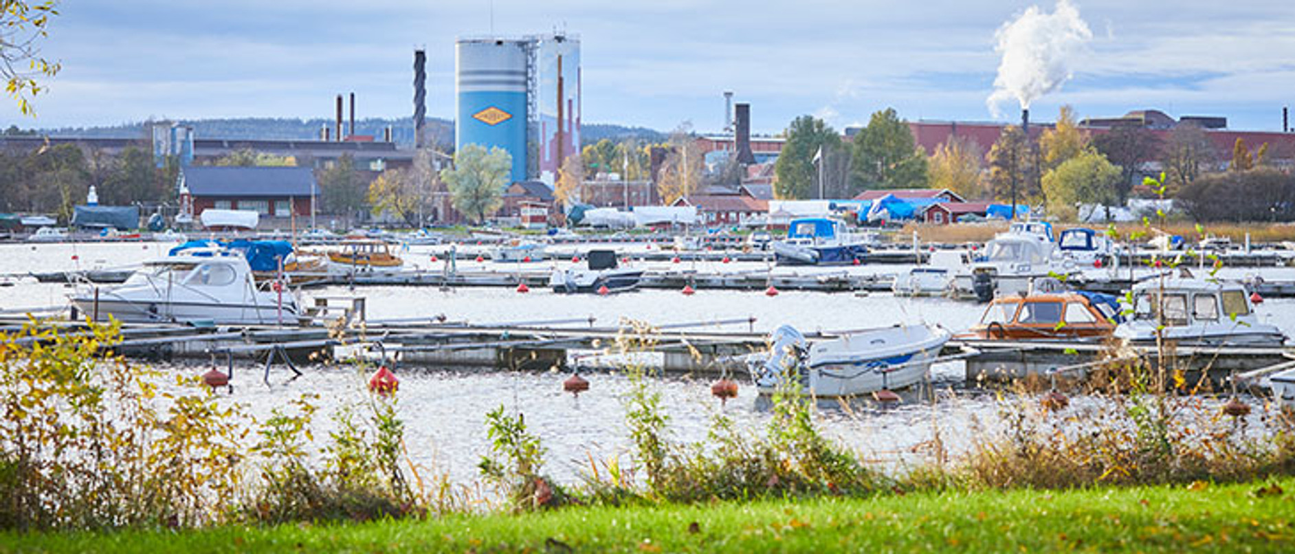 En hamn full av båtar intill en industri.